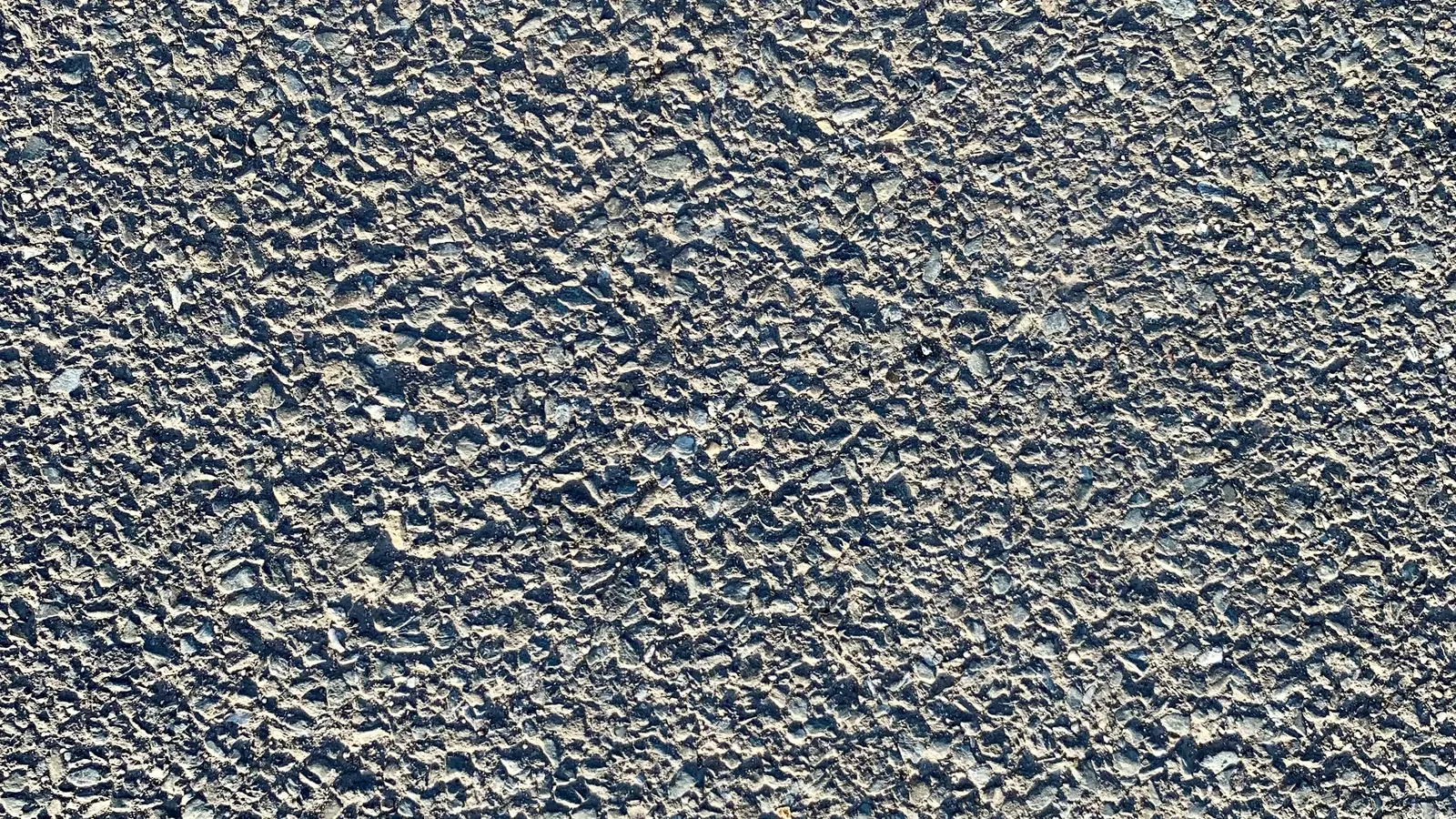 Close-up of dense, uniform, crack-free asphalt pavement texture, the finish loose gravel cannot match