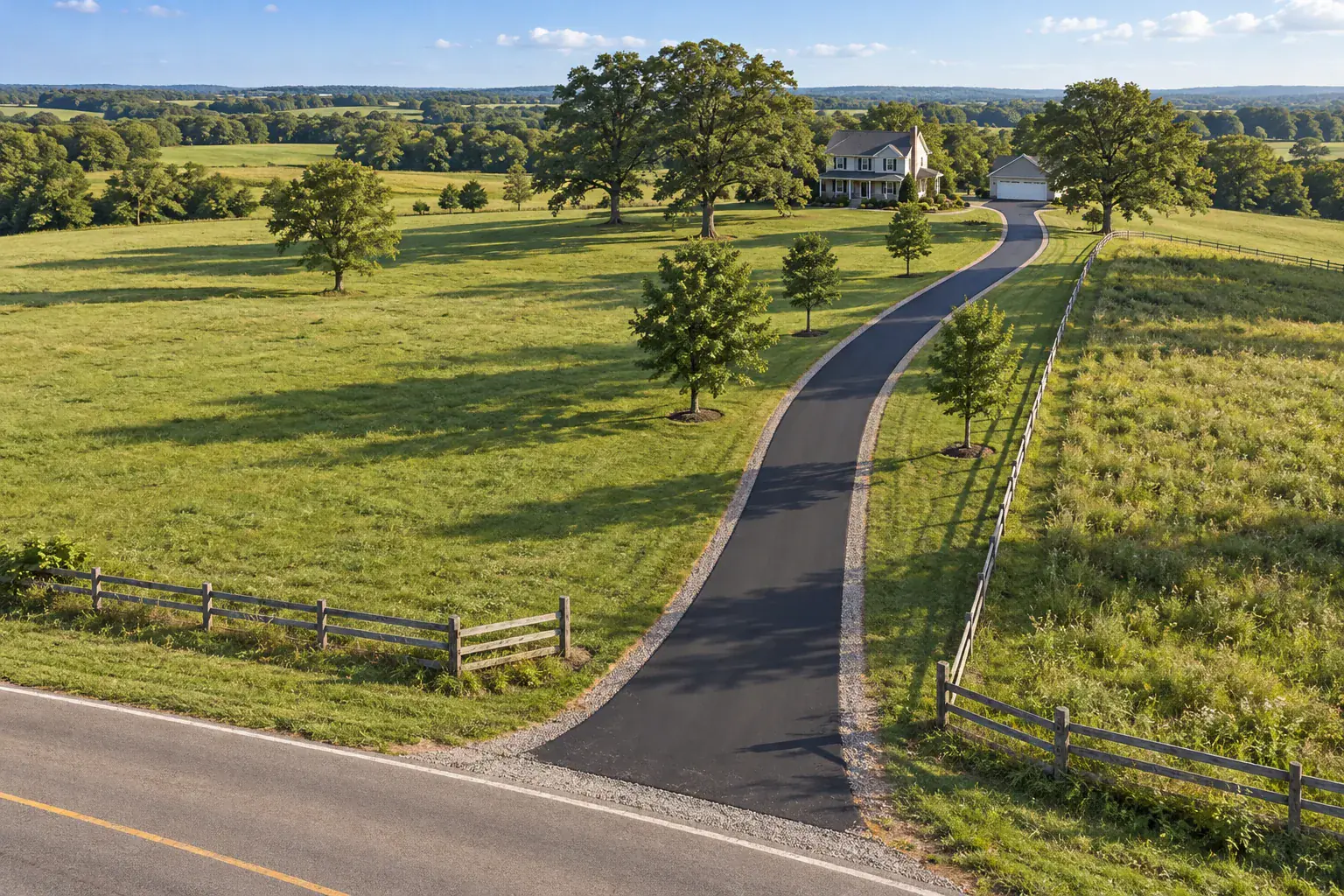 Aerial view of a long single-lane asphalt driveway running through fields to a rural house